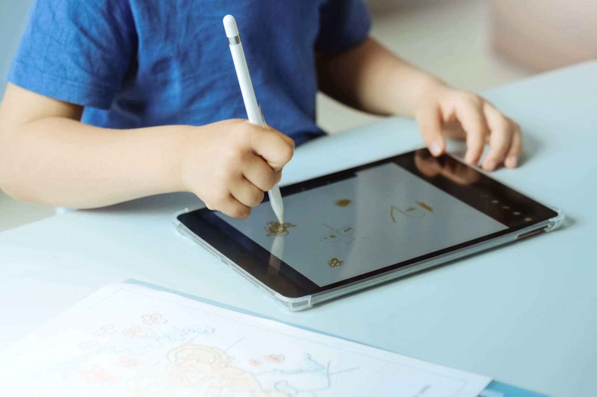 Child using a tablet with a stylus to draw